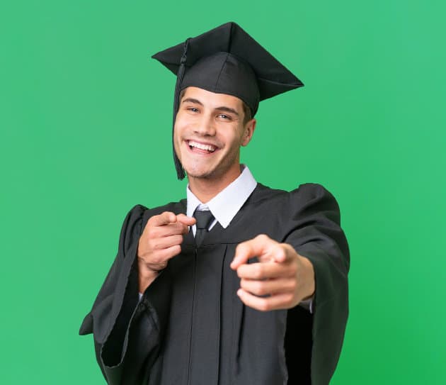 Graduate looking happy, wearing mortarboard and robe, pointing at camera